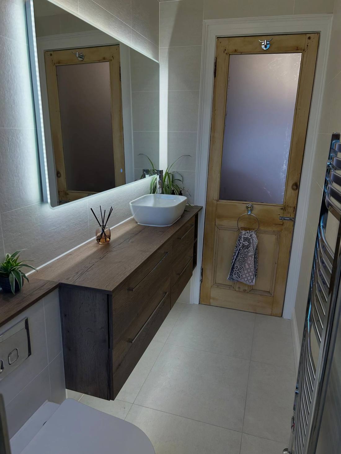 Finished bathroom with fitted vanity unit, basin and backlit mirror